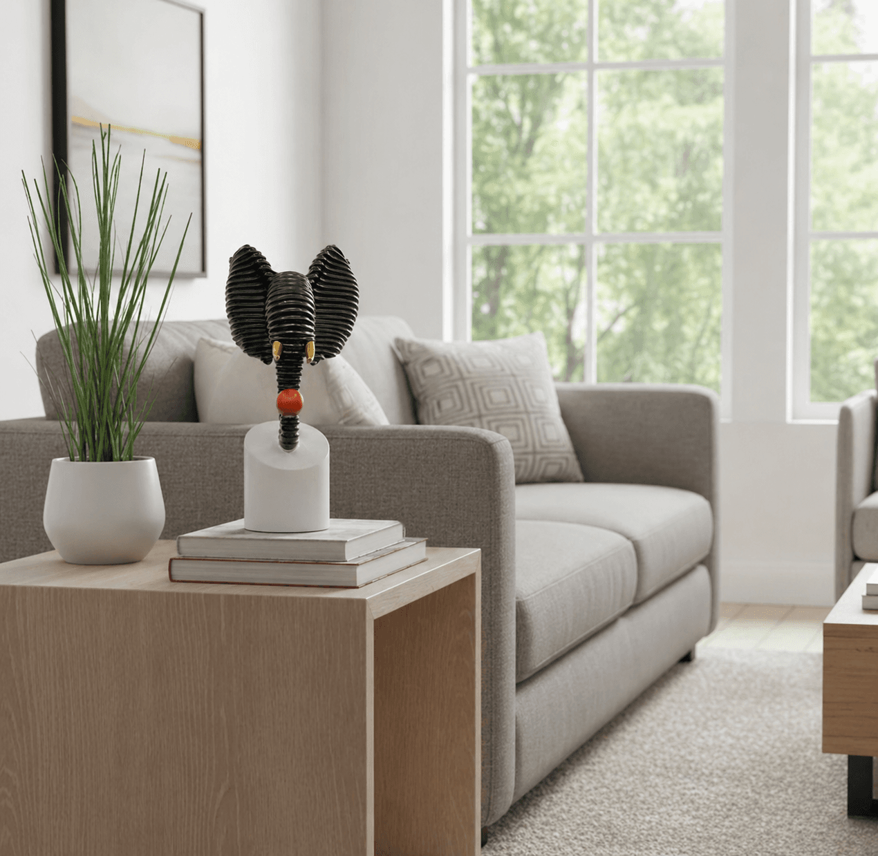Abstract black textured elephant head sculpture holding a red ball, displayed on a modern living room side table over decorative books preview 5