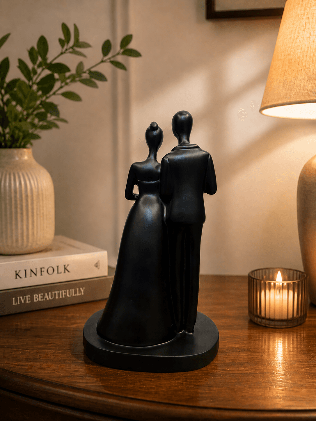 Modern black abstract sculpture of a couple holding a bright red heart, placed on a marble table with candles for romantic bedroom decor preview 3