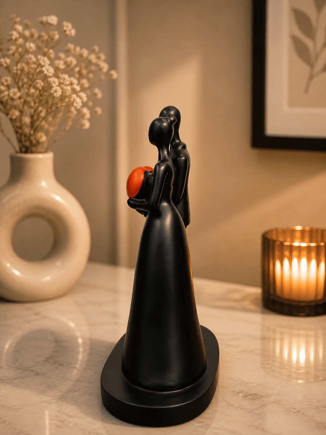 Modern black abstract sculpture of a couple holding a bright red heart, placed on a marble table with candles for romantic bedroom decor preview 4