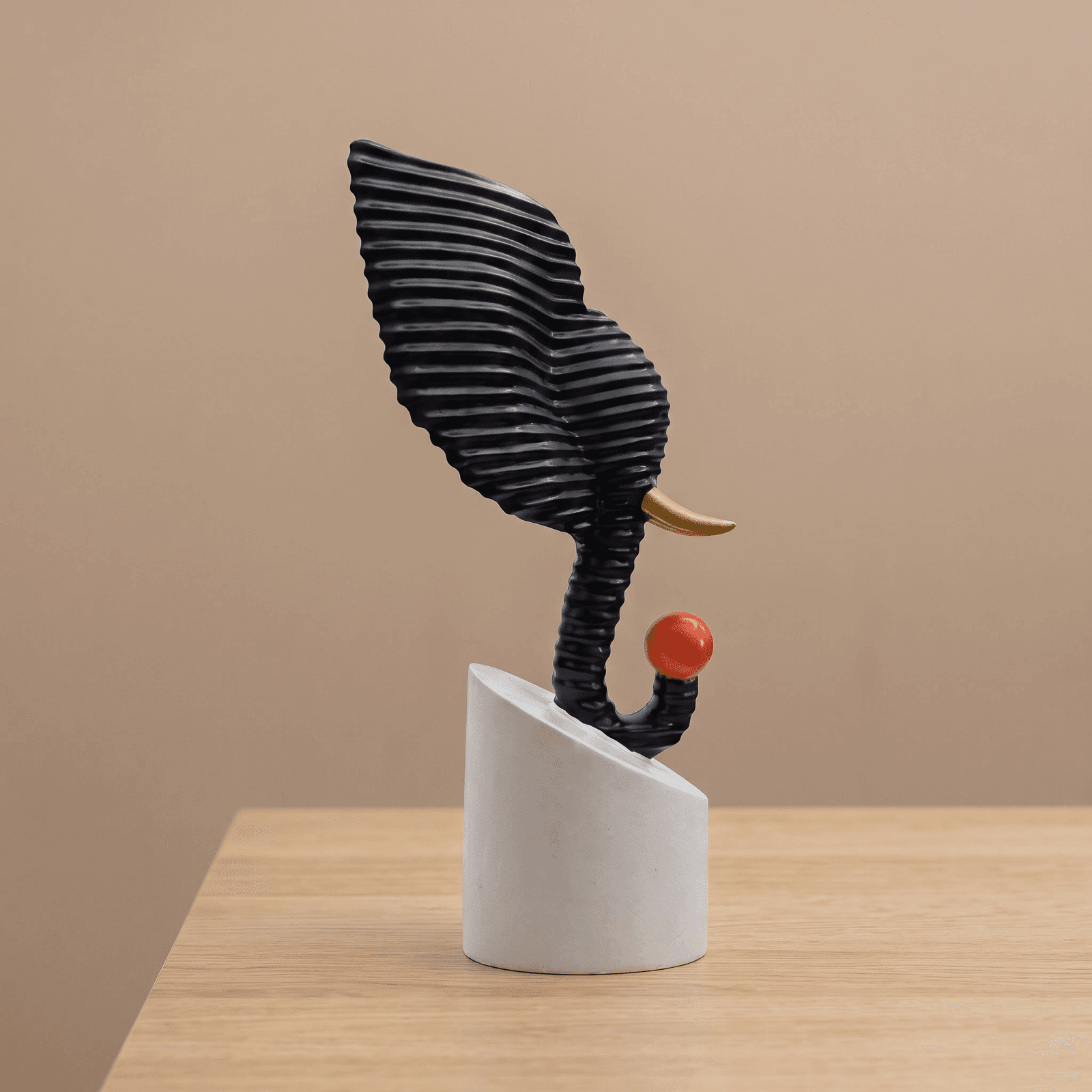 Abstract black textured elephant head sculpture holding a red ball, displayed on a modern living room side table over decorative books preview 2